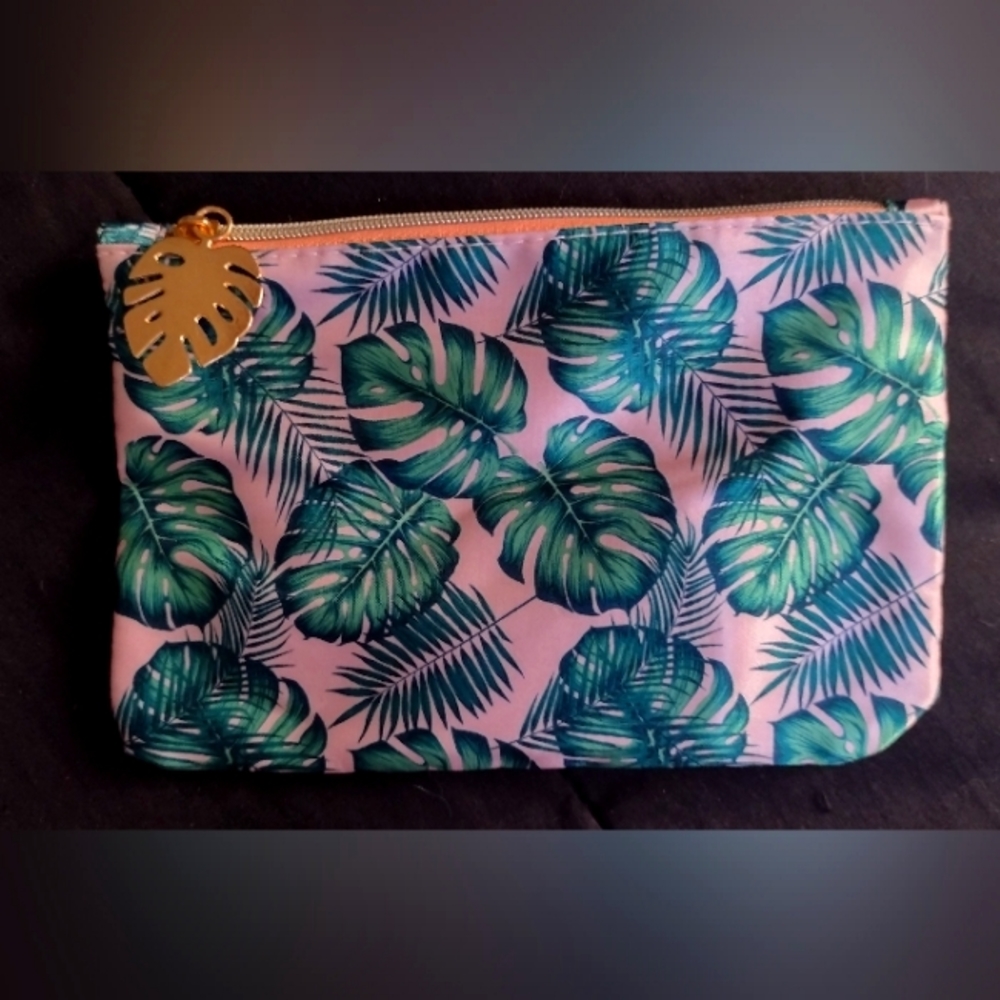 Pink makeup bag with green leafs printed on it.